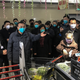 China’s Premier Li Keqiang (hand outstretched) speaks with local residents as he visits a supermarket amid a deadly virus outbreak in Wuhan in China’s central Hubei province on January 27, 2020